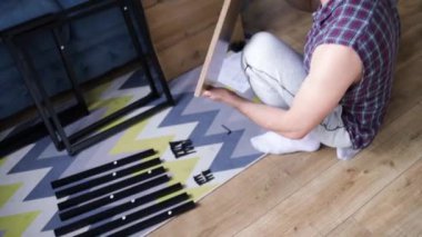 DIY çatı katı tarzı masa montaj işlemi evde yapılıyor. Mobilya döşemesi. Yeni ev ve mobilya montajı yapan adam bunu kendi başına yapıyor. Kattaki talimatlara göre, kutudan itibaren erkek montaj tablosu.