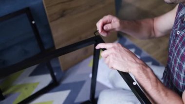 DIY çatı katı tarzı masa montaj işlemi evde yapılıyor. Mobilya döşemesi. Yeni ev ve mobilya montajı yapan adam bunu kendi başına yapıyor. Kattaki talimatlara göre, kutudan itibaren erkek montaj tablosu.