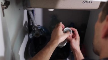 Tesisatçı sızıntıyı tamir ediyor. Esnaf boruyu tamir etmek için lavabonun altında yatıyor.. 