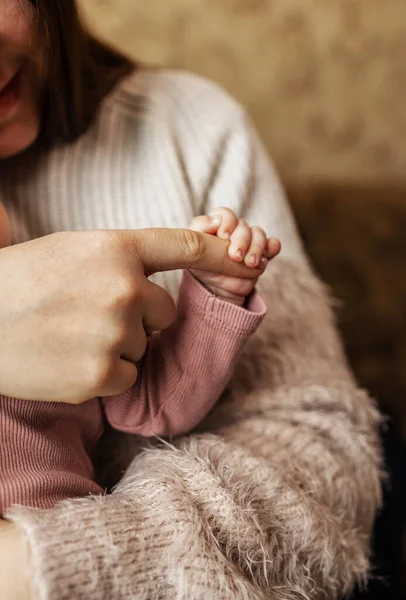 Annenin elinde bir bebeğin küçük elinin yakın çekimi.