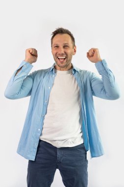 Beyaz arka planda izole edilmiş başarıyı kutlayan mutlu genç bir adamın portresi.