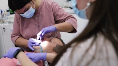 Diş sağlığı kliniğindeki hastayı tedavi eden bir dişçi ve asistanın kapatılması