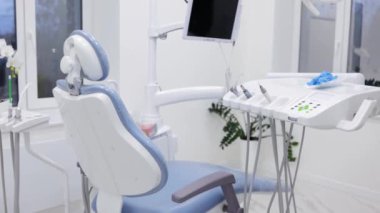 Klinikteki boş beyaz ve açık mavi dişçi ofisi, ekipman, bilgisayar, dişçi koltuğu ve sondaj makinesi..