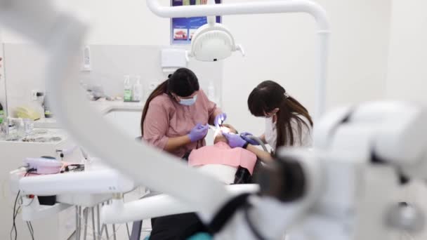 在诊所的专业实验室里 人们的健康和牙科保健 妇女与助手一起作为牙医工作 来访的年轻人作为客户 — 图库视频影像