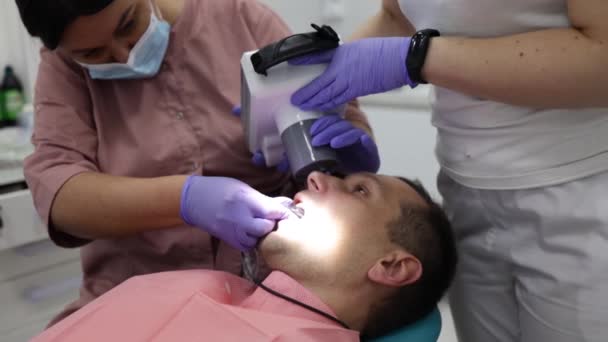 在诊所的专业实验室里 人们的健康和牙科保健 妇女与助手一起作为牙医工作 来访的年轻人作为客户 — 图库视频影像