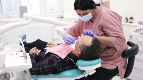 年轻的女牙医牙齿矫正师的接待处更换托架 凝胶粘合 — 图库视频影像