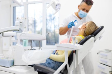 Erkek diş hekimi diş kliniği genç kadın hastada tedavi. Diş işaretleyiniz.