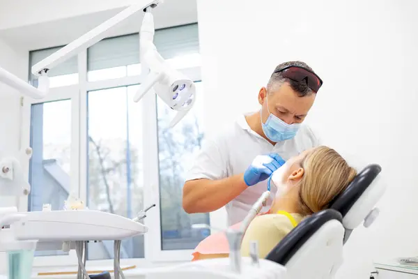 Erkek diş hekimi diş kliniği genç kadın hastada tedavi. Diş işaretleyiniz.