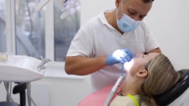 Erkek diş hekimi diş kliniği genç kadın hastada tedavi. Diş işaretleyiniz.