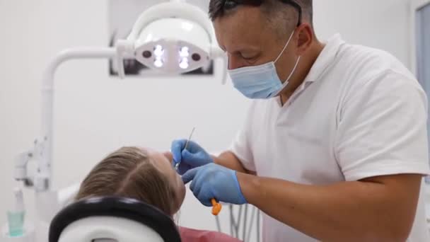 男性の歯科医のクリニックで若い女性患者に歯を治療します 歯科検診 — ストック動画