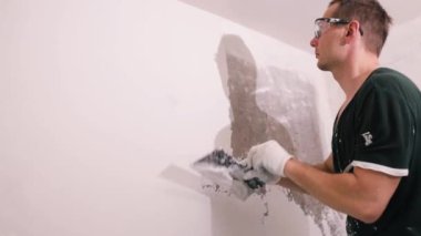 Eller sıva ustası inşaat işçisi mala vuruyor, duvara sıva yapıyor, yakınlaştırıyor..