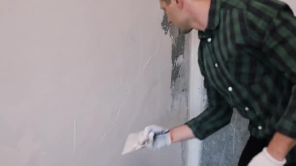 Mains homme plâtrier travailleur de la construction au travail avec truelle, plâtrage d'un mur, gros plan.