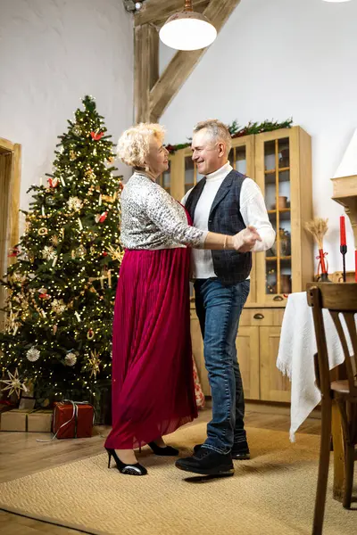 Mature couple dancing at home in front of the Christmas tree