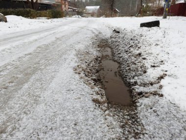 Delikli çamurlu kış yolu. Yol kardan temizlenmedi. İlkbahar buzu. Kar eriyor.