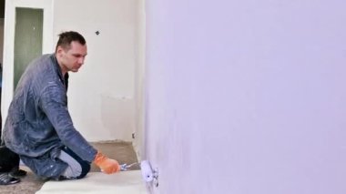 Duvarı pembe boyayla boyayan bir adam. İnşaat işçisi, araç gereç, apartman yenileme.