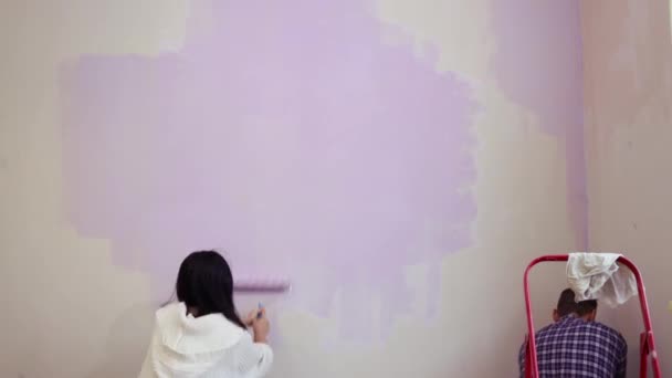 夫妇抱抱滚筒应用紫罗兰色油漆新的居家公寓客厅墙壁 — 图库视频影像