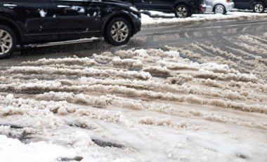 Difficult driving conditions on roads in Spring. Car moving on road with melting snow through puddles