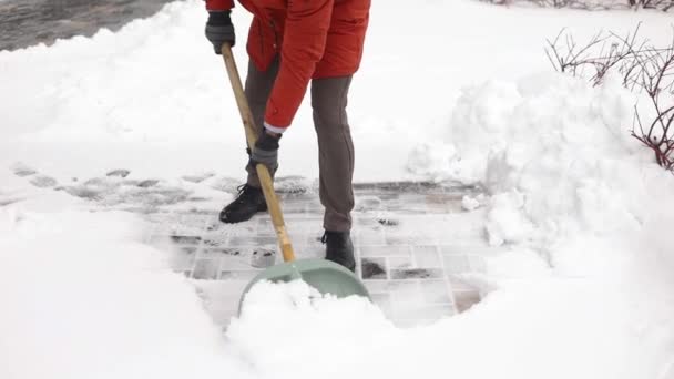 寒い日に家の前に雪を掃除して掃除する男のクローズアップ 冬の日に雪から道路を掃除する 雪と冬の厳しい雪が降る — ストック動画