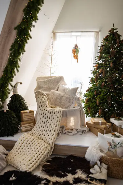 White knitted plaid on sofa with Christmas tree and decorations in the interior of the living room