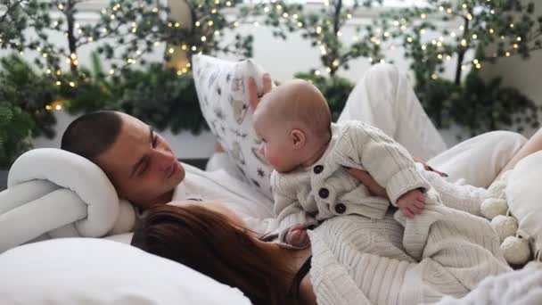 早上快乐的年轻美丽的家庭在舒适的床上休息 快乐的父母和孩子们喜欢在圣诞节的时候在卧室里玩耍 — 图库视频影像