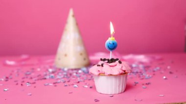 Pastel pembe arka planda yanan renkli mumlu doğum günü pastası. Doğum günün kutlu olsun. Bayram pastasında mum üfleyen kadın..