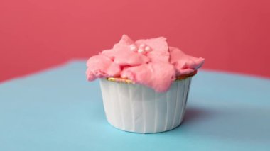 Kremalı lezzetli pembe kek. Mavi arka planda ev yapımı lezzetli kekler dönüyor. Lezzetli pastalar süslüyor..