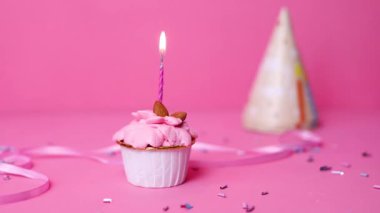 Pastel pembe arka planda yanan renkli mumlu doğum günü pastası. Doğum günün kutlu olsun. Kekin üzerine mum yak..