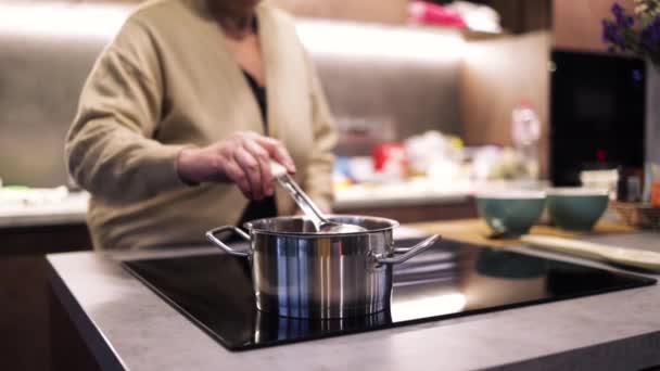 无法辨认的女人在厨房里煮汤 家庭主妇慢吞吞地在家里用勺子搅拌汤 女厨师站在厨房的炉边 — 图库视频影像