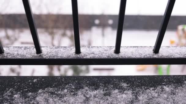 バルコニーに落ちる濡れた雪片の映像を閉じます 家の窓からの冬の雪景色 寒い雪の天気 — ストック動画