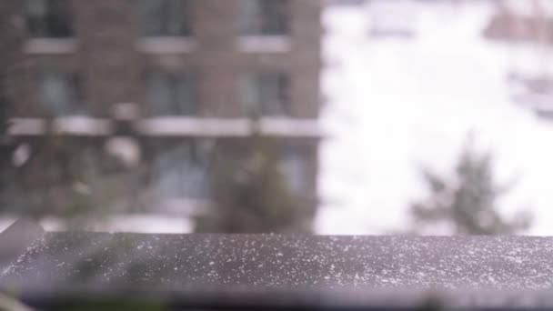 バルコニーに落ちる濡れた雪片の映像を閉じます 家の窓からの冬の雪景色 寒い雪の天気 — ストック動画
