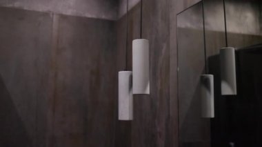 Parlayan ampulleri olan çatı katı tarzı gri tavan lambaları. Spot lambası elektrik kablolarına asılmış beton duvarın arka planına karşı. Kolye Işıkları.