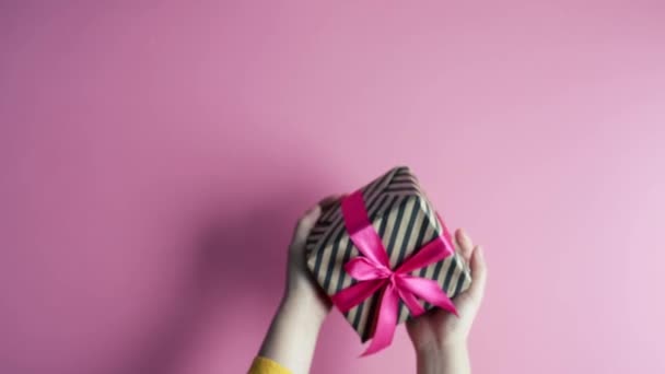 Vrouwelijke Handen Houden Geschenkdoos Roze Achtergrond Bovenaanzicht — Stockvideo