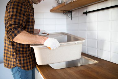 Bir adam mutfağa lavabo yerleştiriyor. Mutfak mobilyalarının montajı.