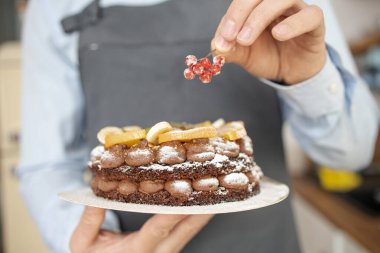 Lokanta Mutfağı 'nda yakın plan erkek aşçı Tabak Odaklı Ekleme Son Malzemesi Elle. Modern Ev Mutfağında Kek Yemekleri Pişiriyorum. Lezzetli Lezzetli Yemekler. İştah açıcı Tatlı Yemeği Hazırlanıyor 