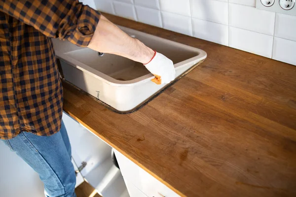 Bir adam mutfağa lavabo yerleştiriyor. Mutfak mobilyalarının montajı.