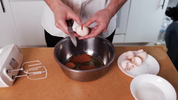 男用手用刀打碎鸡蛋 一个人把鸡蛋打成一碗 在家里准备面团的过程 一个人把鸡蛋分成碗 自制的食物 在家做饭 — 图库视频影像