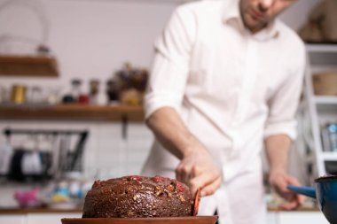 Bir adam evde çikolatalı pasta hazırlıyor..
