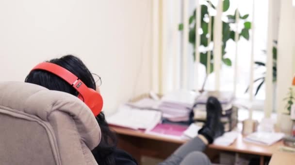 現代オフィスで休憩しているヘッドフォンを持つ幸せな若いビジネス女性 — ストック動画