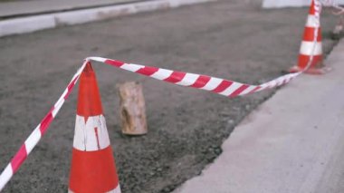 Kırmızı ve beyaz uyarı bantları, tehlikeli inşaat alanının sınırlarını belirleyen güvenlik şeritlerini genişletti. Şehir yolunda tamirat, yaya yolunun yeniden inşası..
