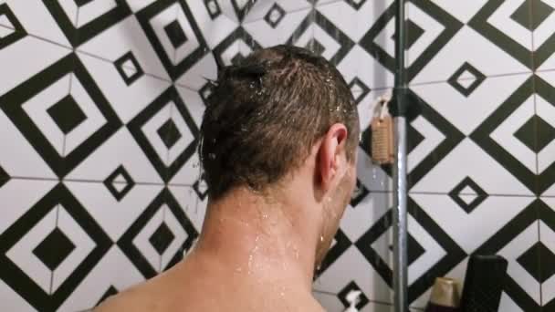 在家里浴室里洗头洗澡的男人 无法辨认的人从后面用现代化的浴室在暖水浴中冲洗洗发水和护发素 — 图库视频影像