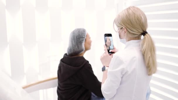 Lekarz Kosmetolog Fotografuje Proporcje Twarzy Klientki Telefonem Komórkowym Przed Zabiegiem — Wideo stockowe