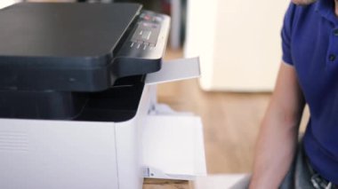 Yazıcı tamircisi. Bir erkek tamirci, tamirata başlamadan önce yazıcıyı kontrol eder..