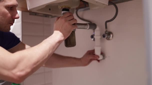 バスルームのシンクで作業するプラスチック製 配管システムの漏れを修正し シンクサイフォンを収集する — ストック動画