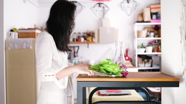 一位年轻的亚洲女士在厨房的花瓶里放了一束郁金香 — 图库视频影像
