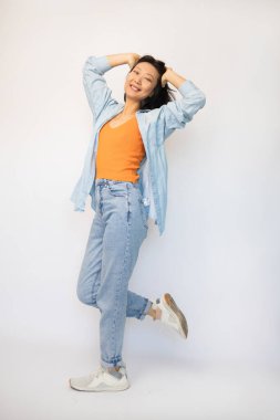 Beyaz arka planda izole edilmiş genç, neşeli Asyalı kadının tam boy fotoğrafı..