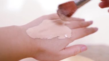 Yapısını ve tonunu kontrol etmek için bir kat makyaj malzemesi fırçalamak.