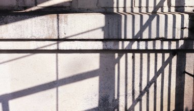 Çelik çitin gölgesi eski beton beyaz duvarın üzerinde, bir günde. düz çizgiler.
