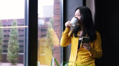 Asyalı bir kadın mutfakta dinleniyor akıllı telefon, internetten mal seçiyor, internetten yemek siparişi veriyor. Modern kablosuz teknoloji hayatı basitleştirir, kolay e-servis kullanımı kavramı