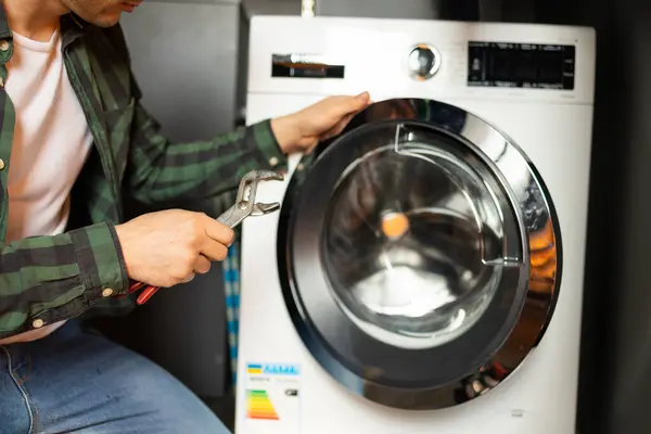 Handyman fixing a washing machine in the kitchen.