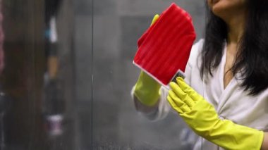 Bir kız banyoda ayna yıkıyor. Eller yukarı. Temizlik konsepti. Ev hanımı çalışıyor. Genç ve güzel bir kadın banyodaki aynayı temizliyor. Hizmetçi evi temizliyor..